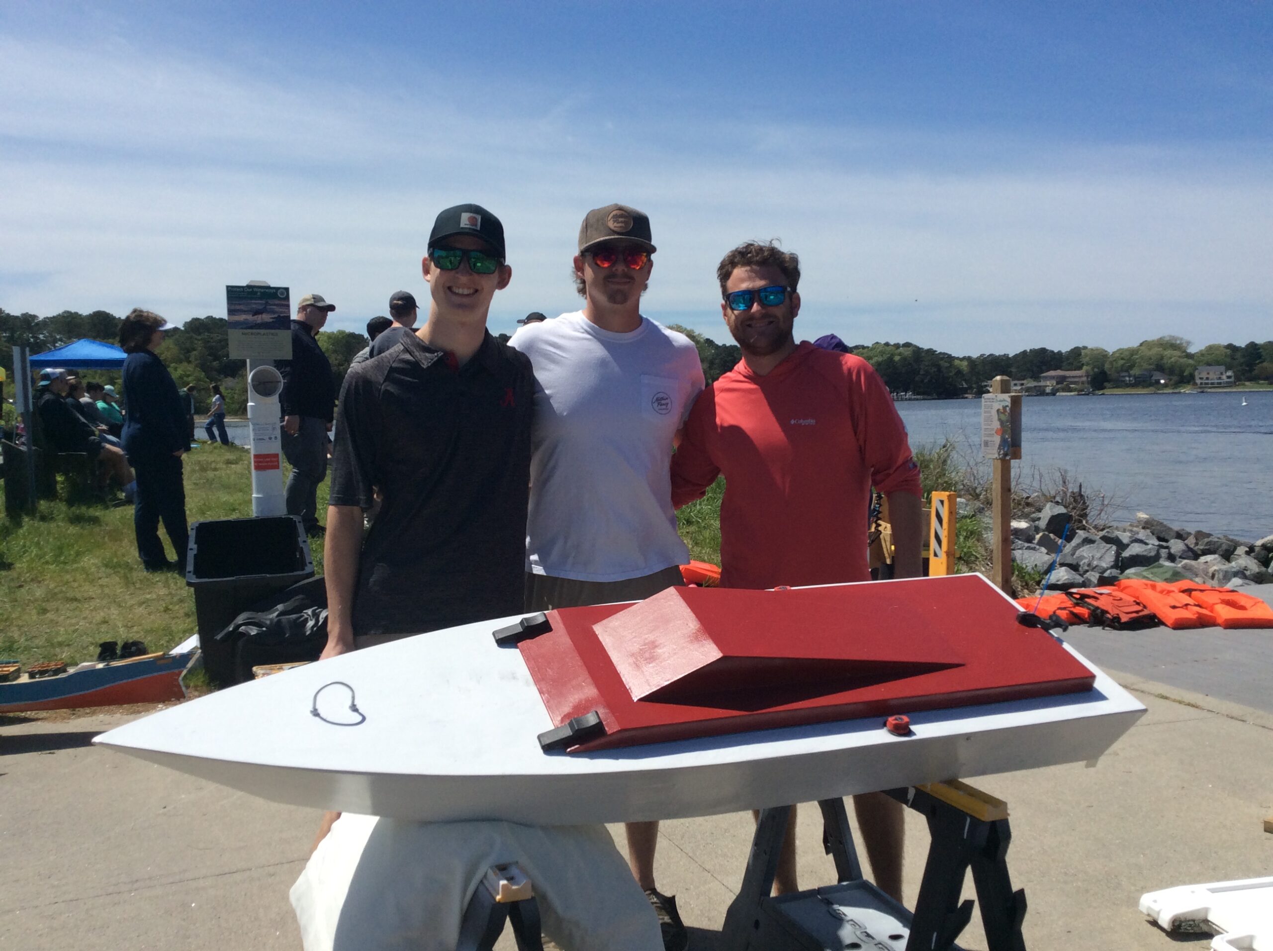 Reid Leger, Nick Pounders, and Richard Brigstocke stand behind their winning electric boat at the PEP 2024 competition. 