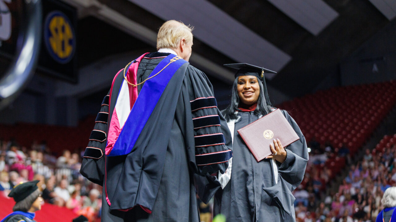 a young lady shakes Dr. Bell's hands as she gets her degree