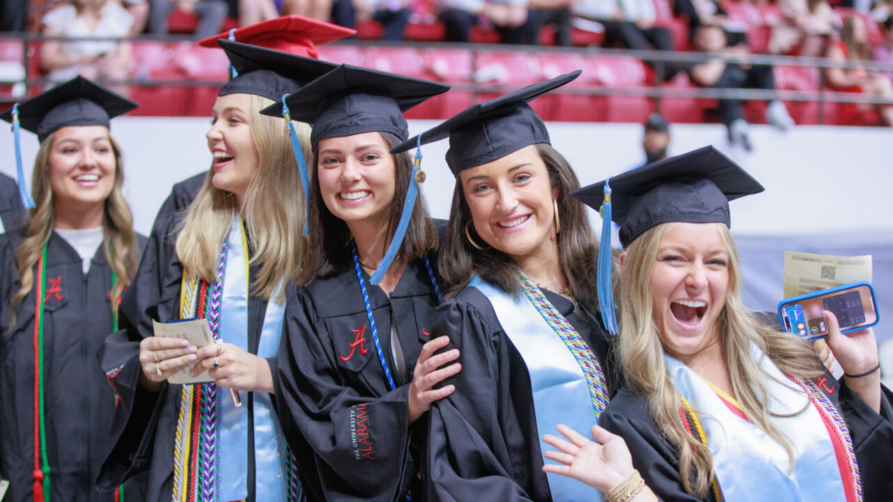 a group of new graduates smile excitedly after getting their degrees