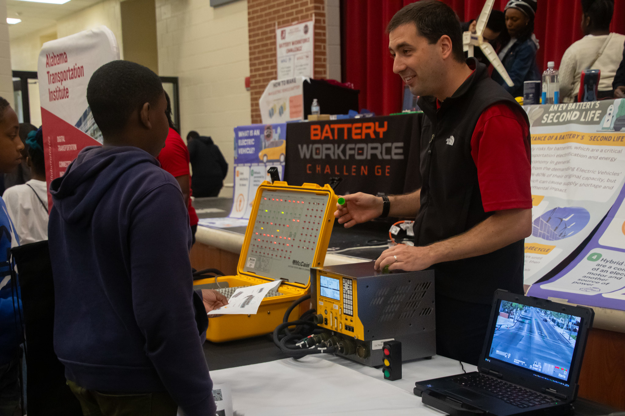 Researcher with the Battery Workforce Challenge demonstrates a battery for two students.