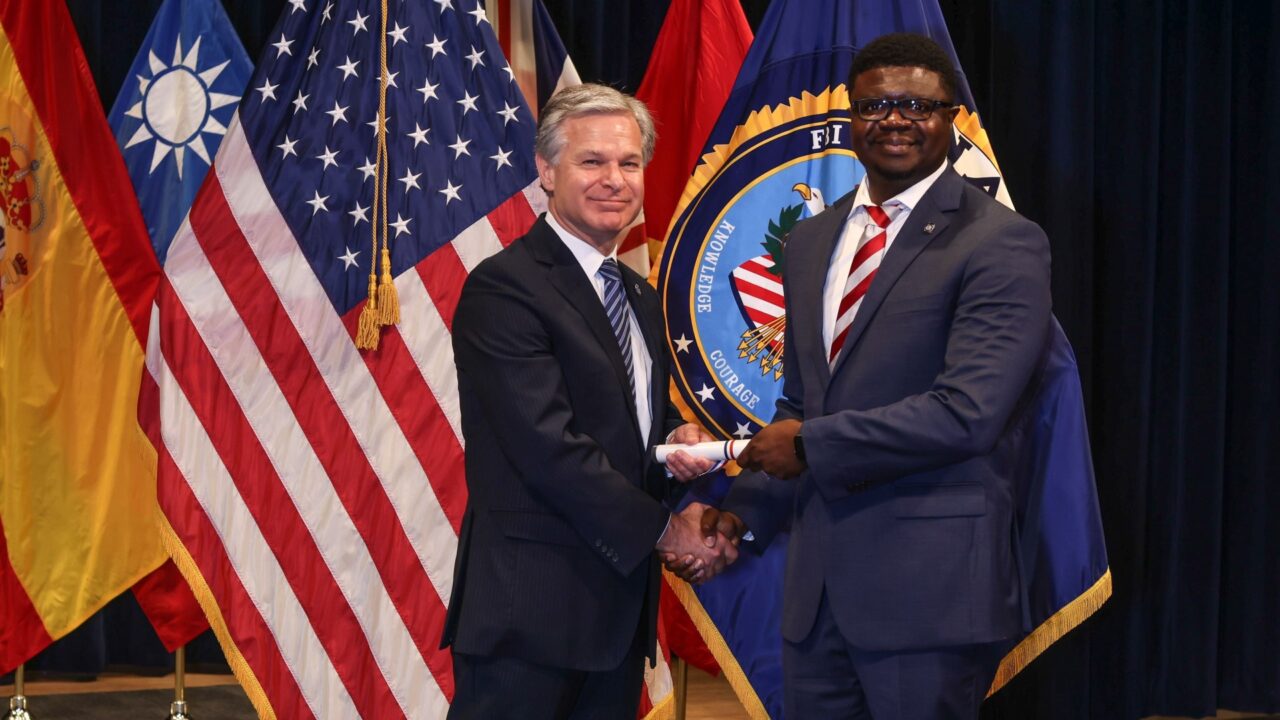 UAPD Deputy Police Chief Micah Rodgers shakes hands with FBI Director Christopher Wray.