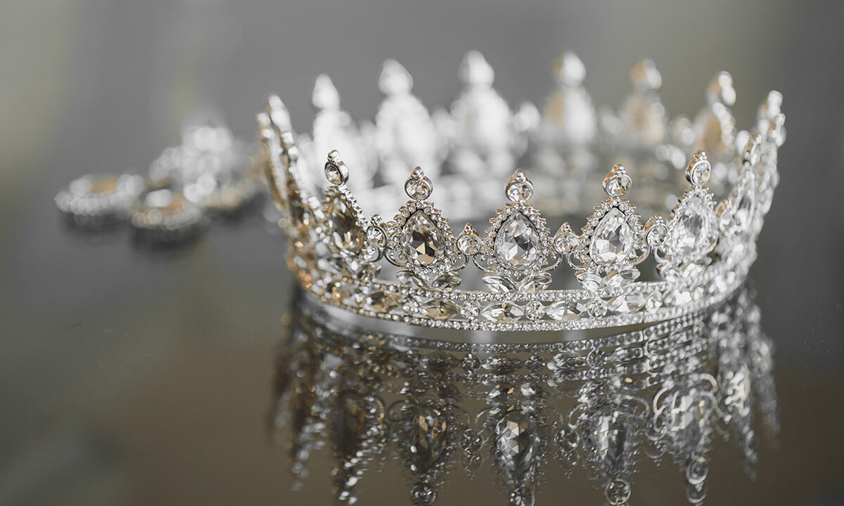 A diamond-encrusted crown sits on a shiny table.