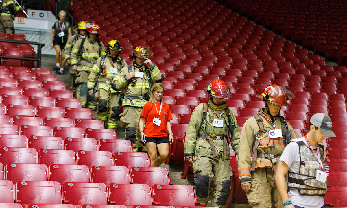 Firefighters and others walk down stairs at Coleman Coliseum.