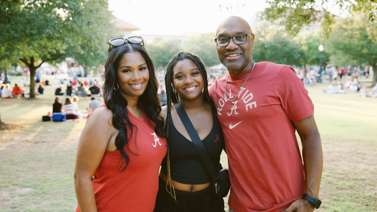 a young woman smiles with her parents during a Family weekend event