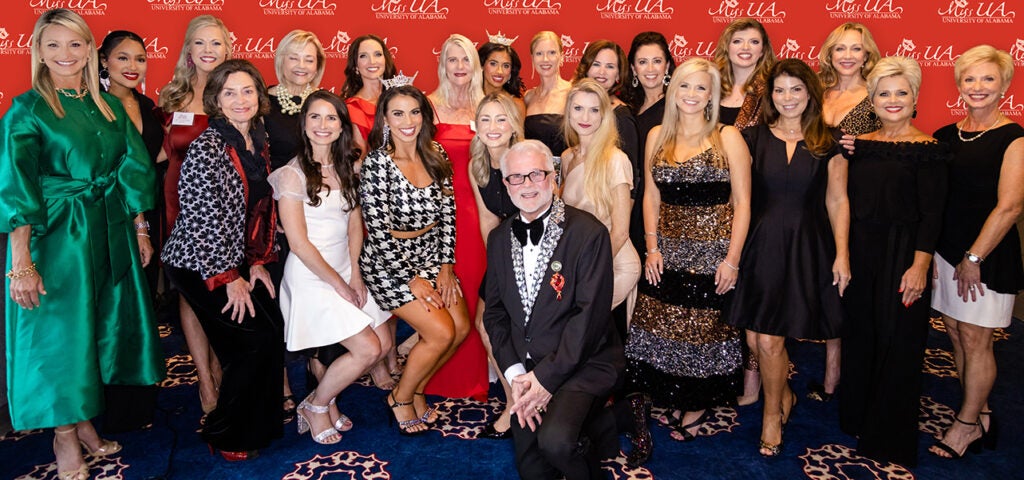 A group of men and women post for a photo at the Miss UA pageant.