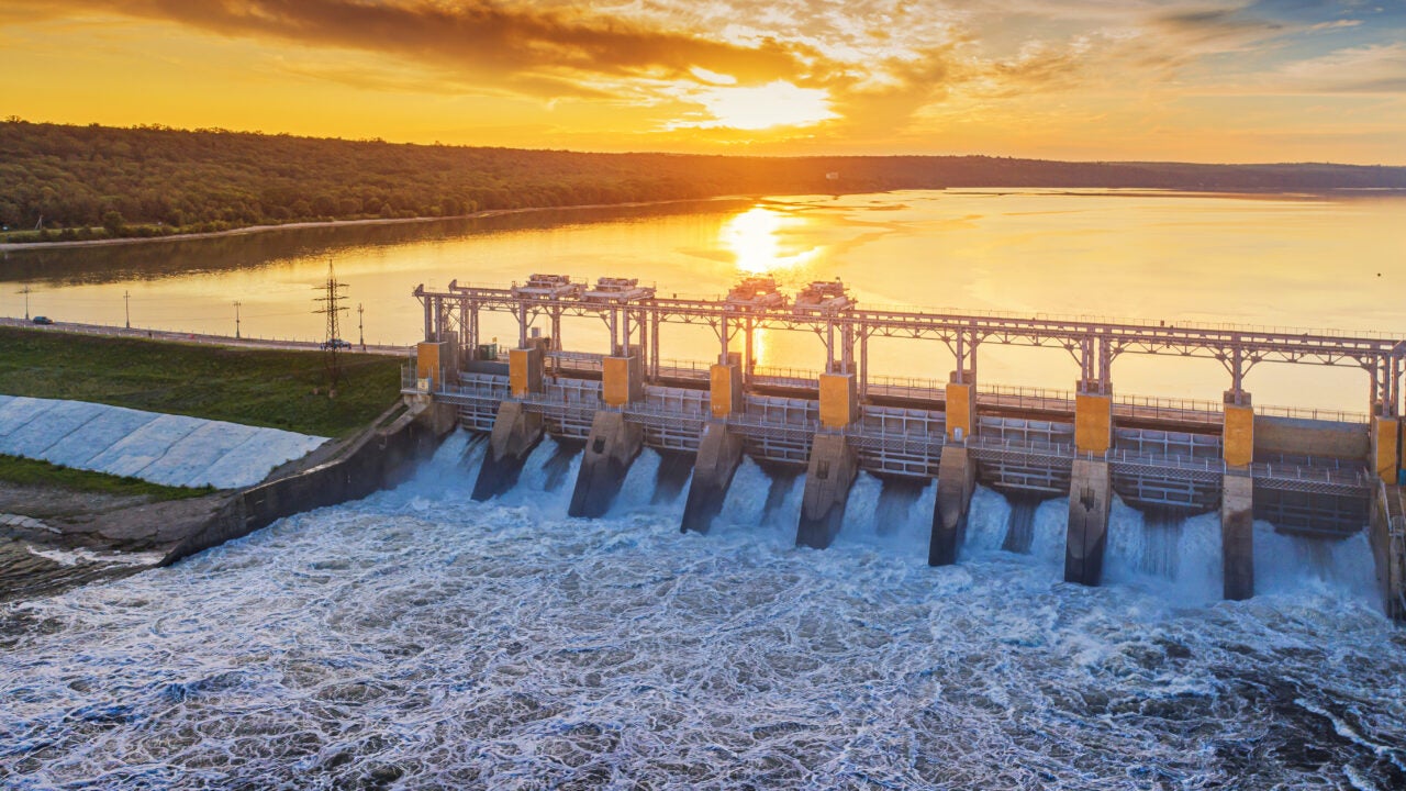 Water flows through a hydroelectric power plant at sunset