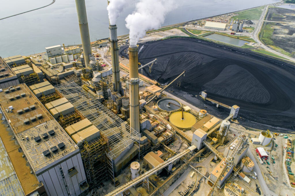 Aerial view of a coal fired power plant with a black pond beside it. 