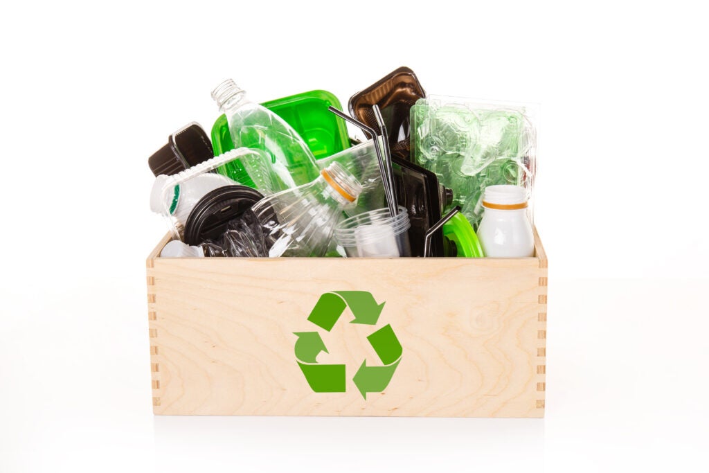 Wooden box marked with a recycling symbol holding a variety of plastic bottles. 