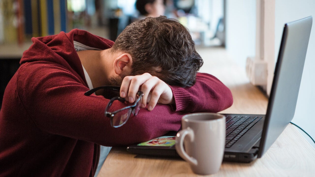 A man leaning over his computer because he's tired