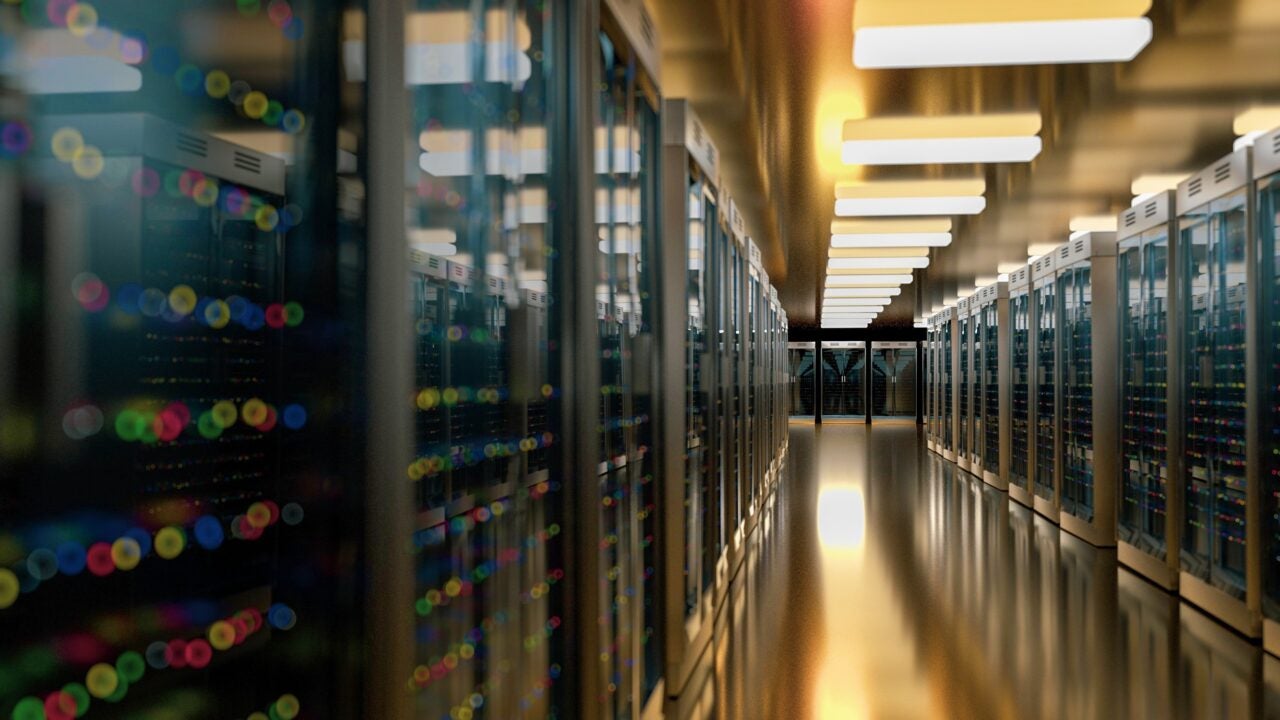 Racks of servers in a data center. View is looking down a long aisle with racks of servers on each side.