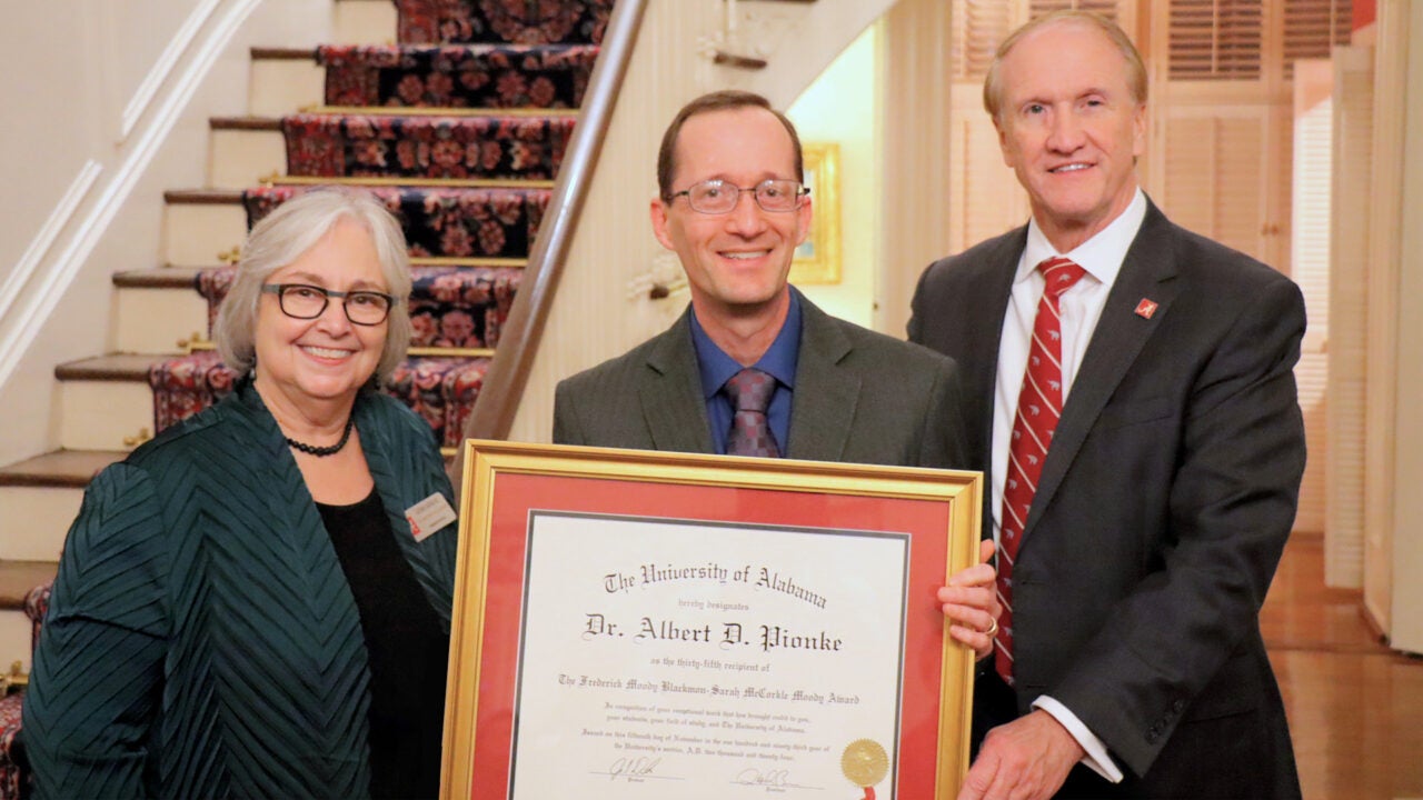 Graduate School Dean Susan Carvalho, Albert Pionke holding the award and President Stuart Bell