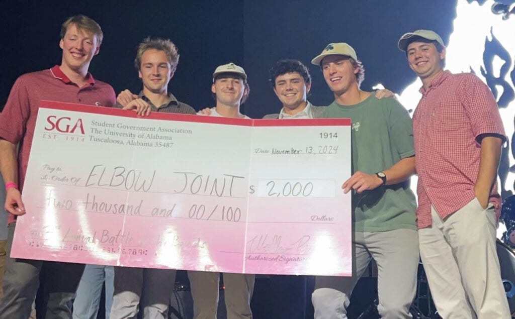 Student music group Elbow Joint poses with large check.