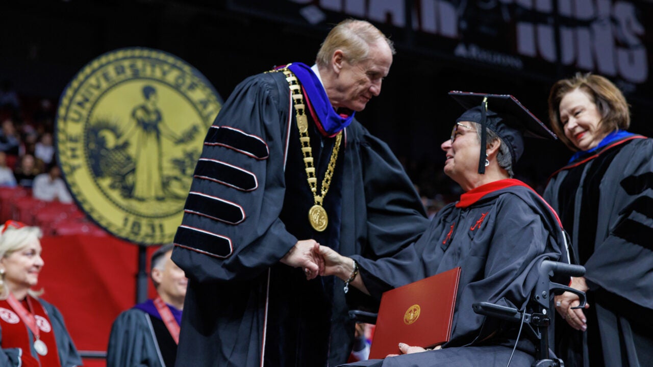 Dr. Bell shakes a graduate's hand