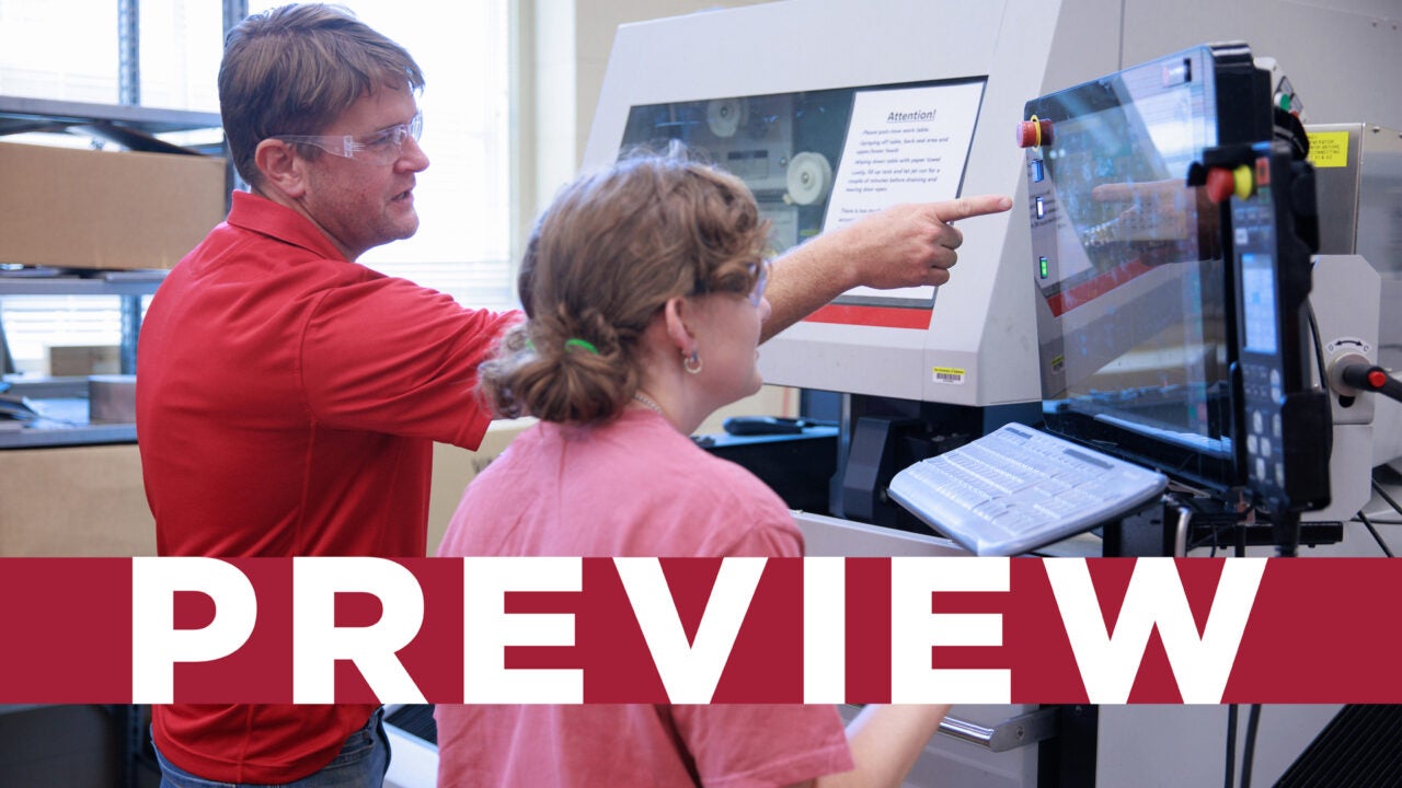 A professor and student conducting research on a large computer in a lab