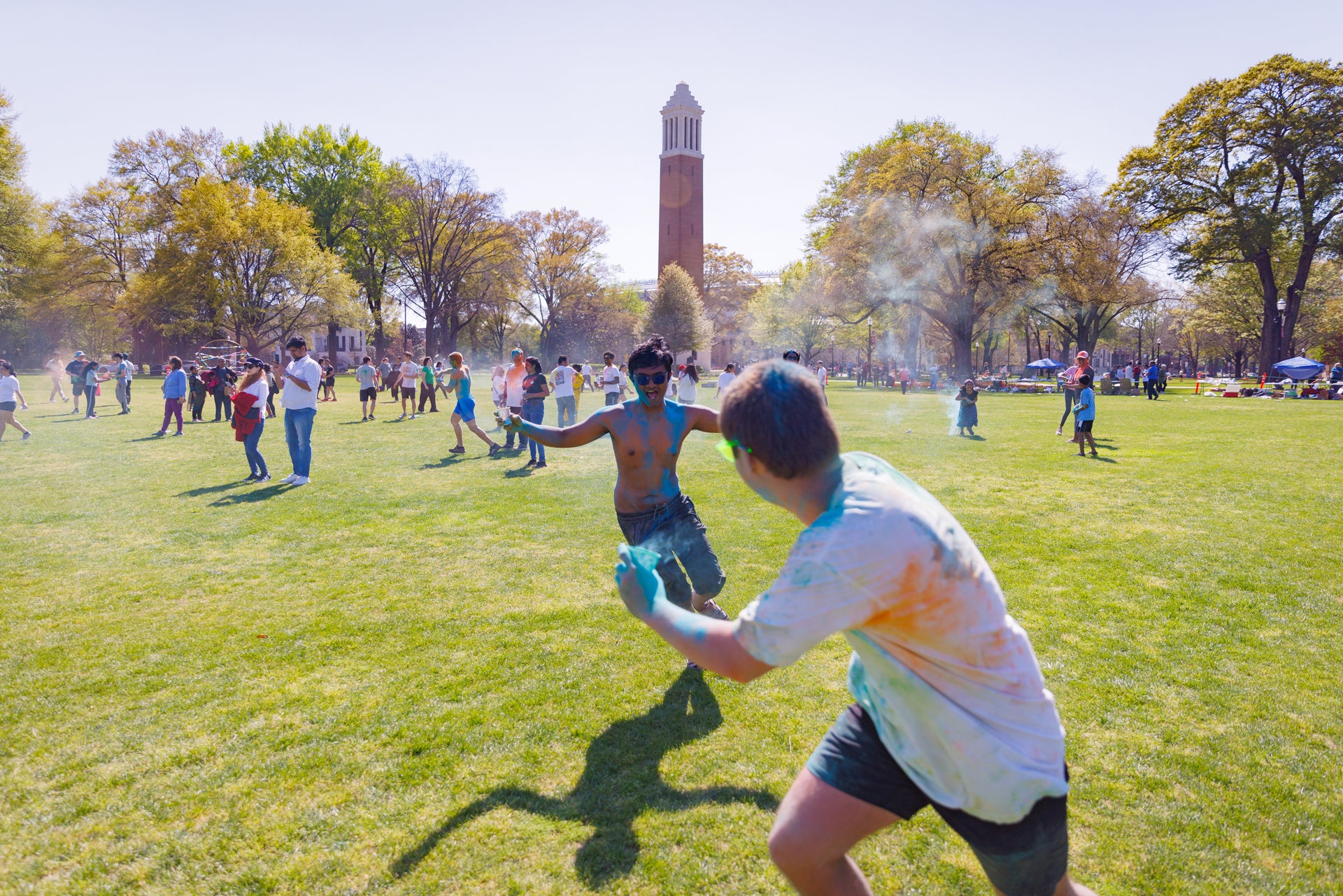 two young students run while throwing colored powder at each other during the Holi fest