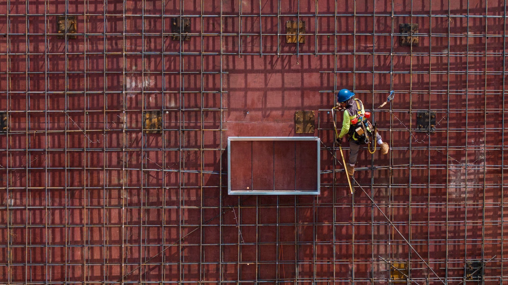 a construction worker hangs from the facade of a building. 