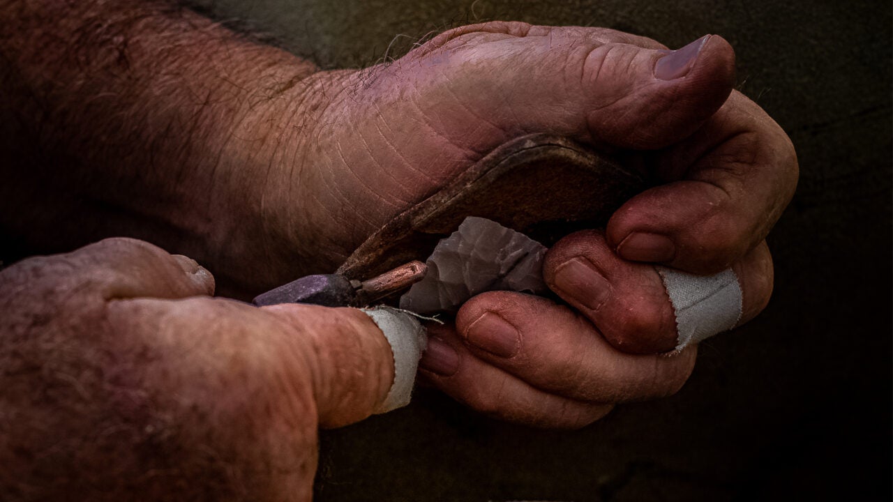 A man flint knapping an arrowhead