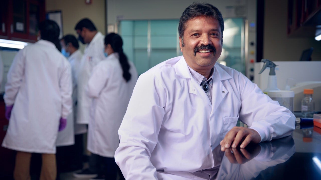 Ravi Kumar in his lab with students studying in the background