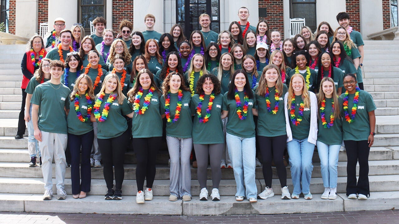 A large group of students stand on the front steps of Reese Phifer Hall.