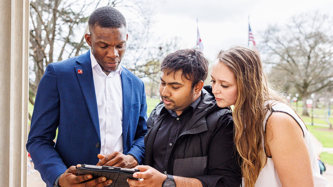 Three people look at a tablet together.