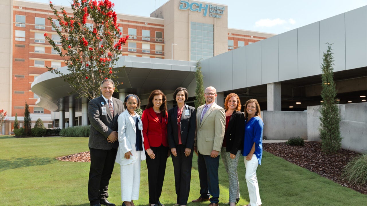 University of Alabama and hospital representatives posing in front of Druid City Hospital