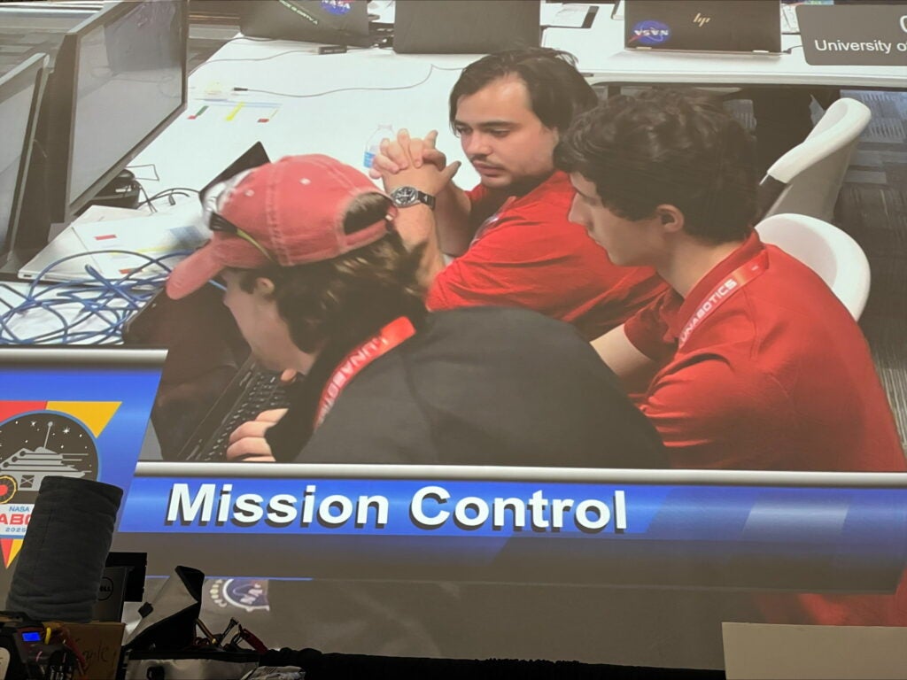 A screen shows members of the UA lunar robotics team in the competition's mission control.