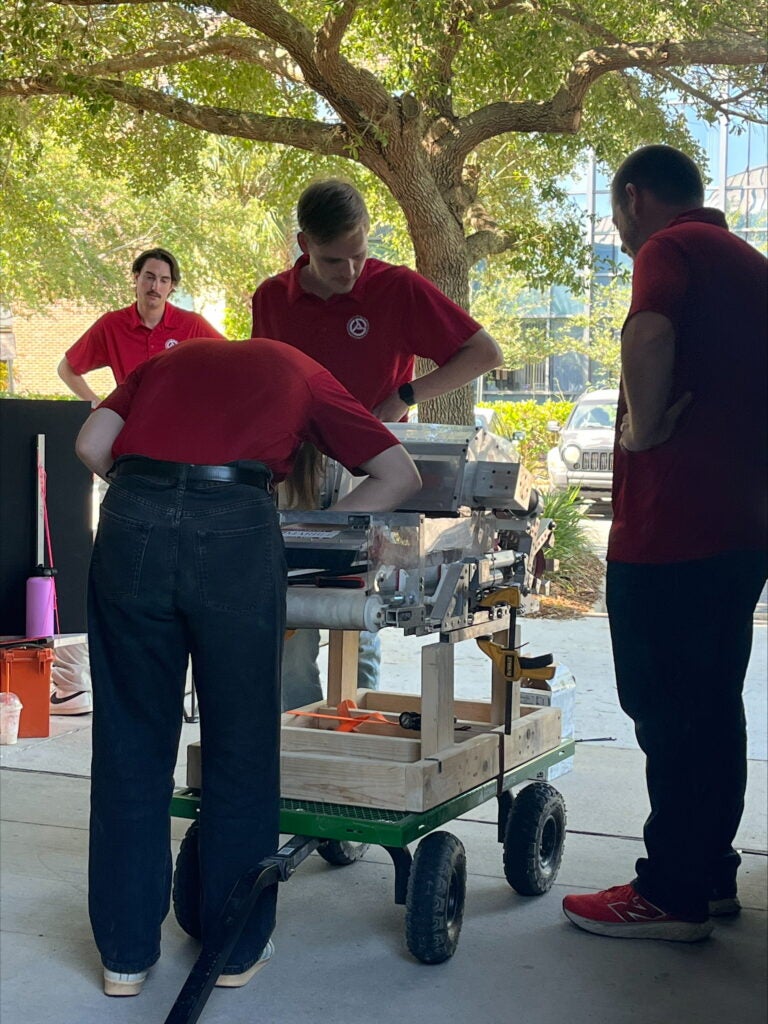Members of the UA lunar robotics team lean over the rover.