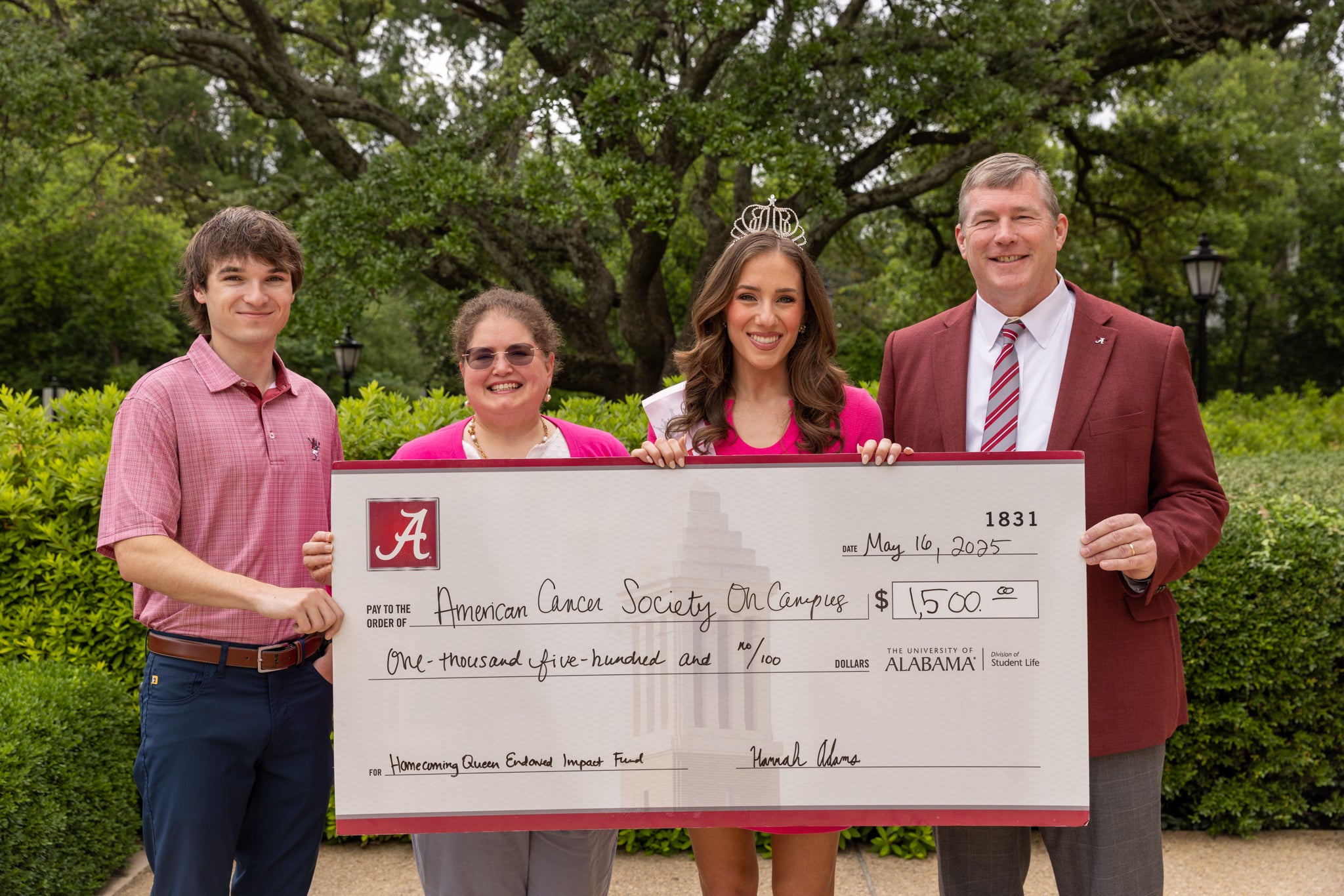four people stand holding a large check