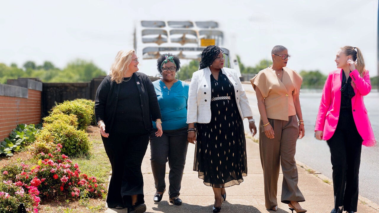 A group of women stand in front of a bridge in Selma.