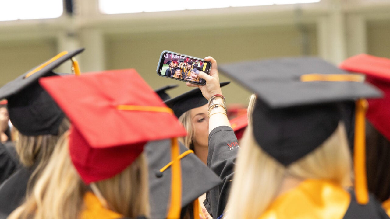 view from the back of a group of young women as they pose for a selfie with a smartphone