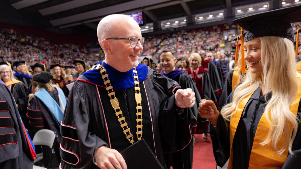 UA President Peter J. Mohler fist bumps a new graduate as he walks to the commencement stage