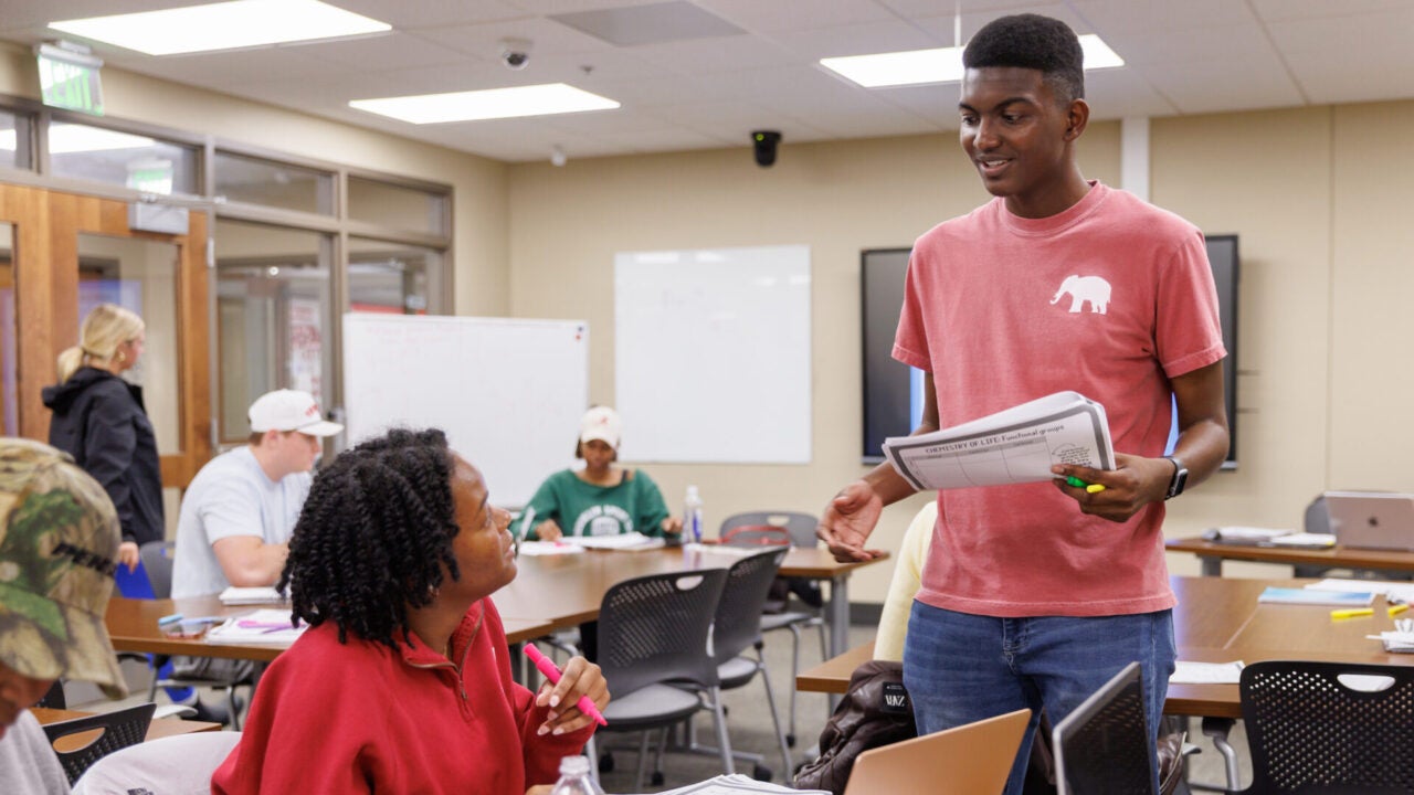 a student stands while tutoring another student in the capstone center for student success