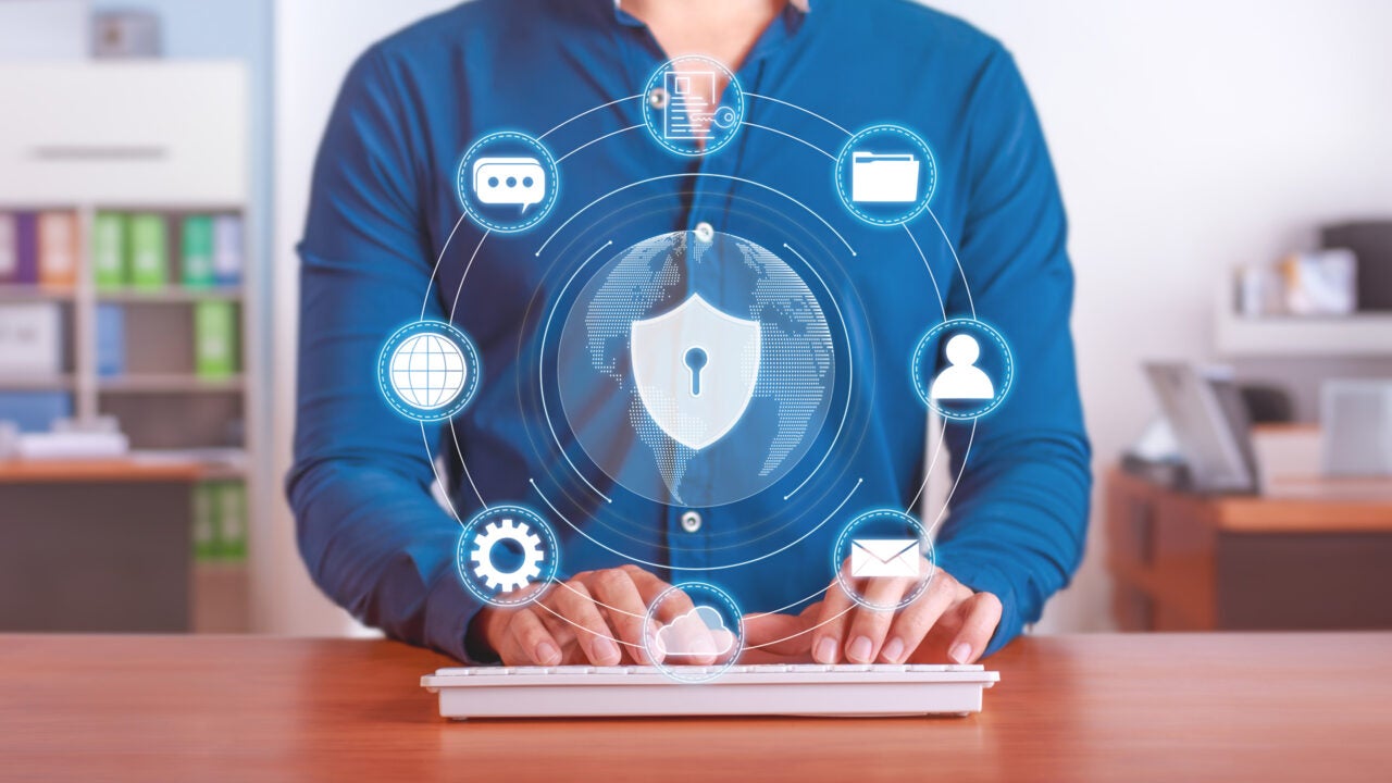 A person behind a keyboard with data elements surrounding a lock
