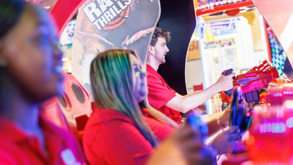 Three students play a car driving game.