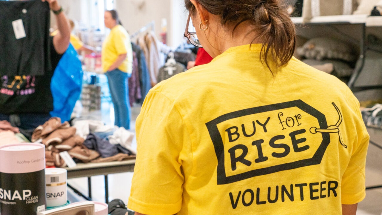 The back of a Buy for RISE volunteer looking at items