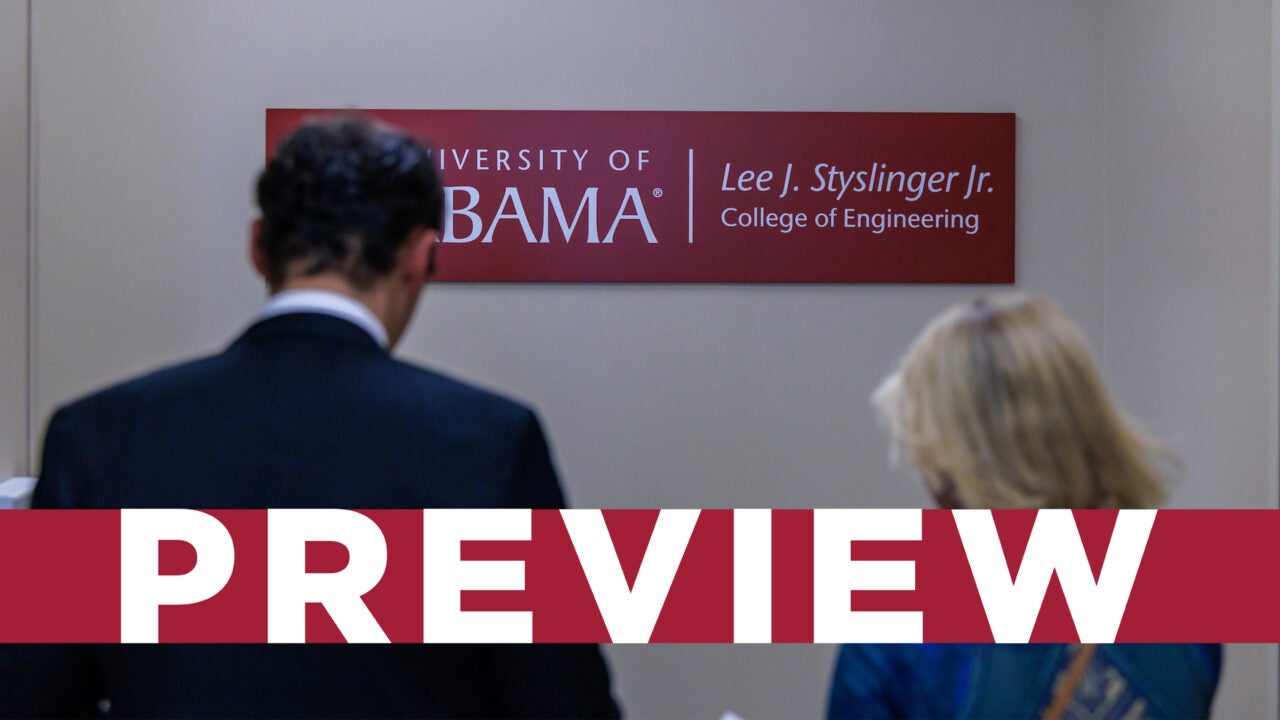 Two people walking with new signage of the Lee J Styslinger Junior College of Engineering sign in the background