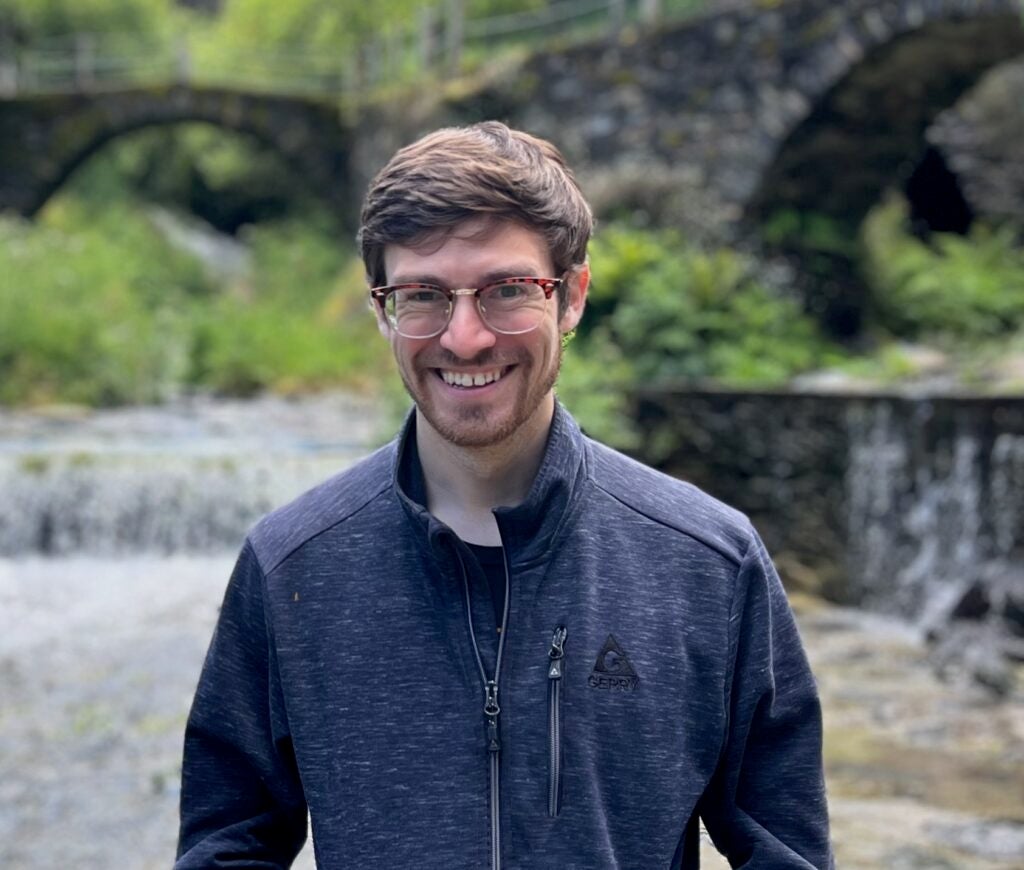 Dr. Samuel Grunblatt standing in front of a blurred background of stone arched bridges. 
