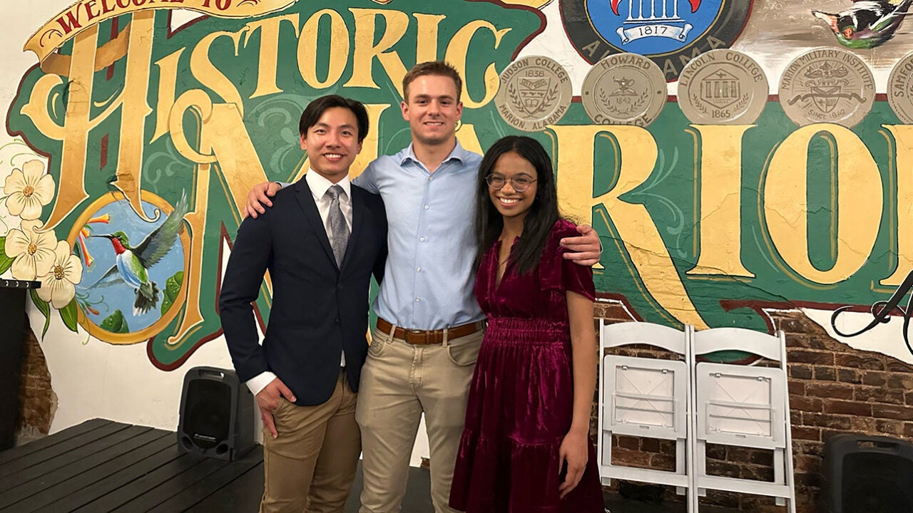 Three Witt Fellows pose in front of a Marion, Alabama sign