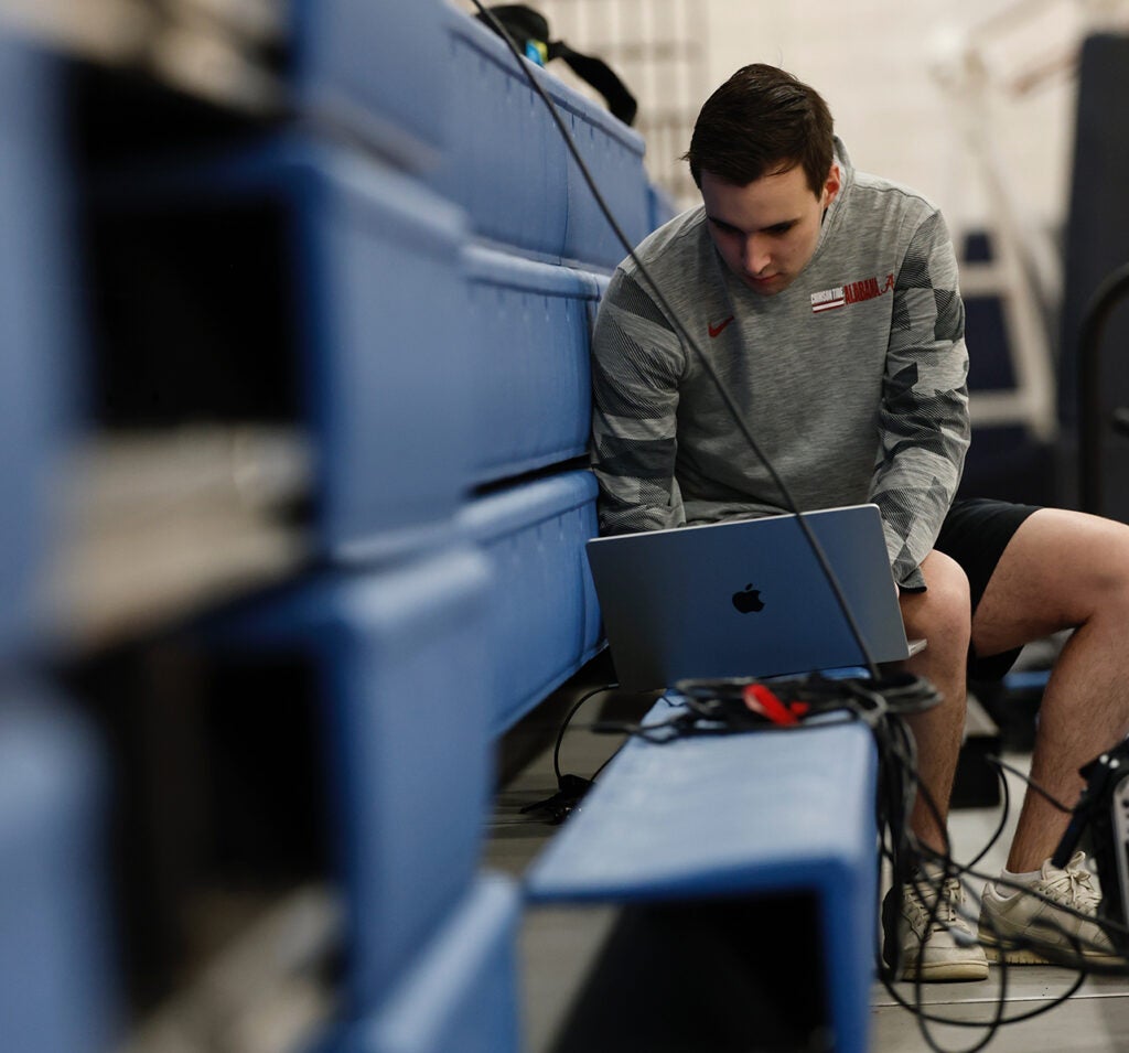 Riley Arnold looking over data collected on a laptop during a UA Men's basketball practice.