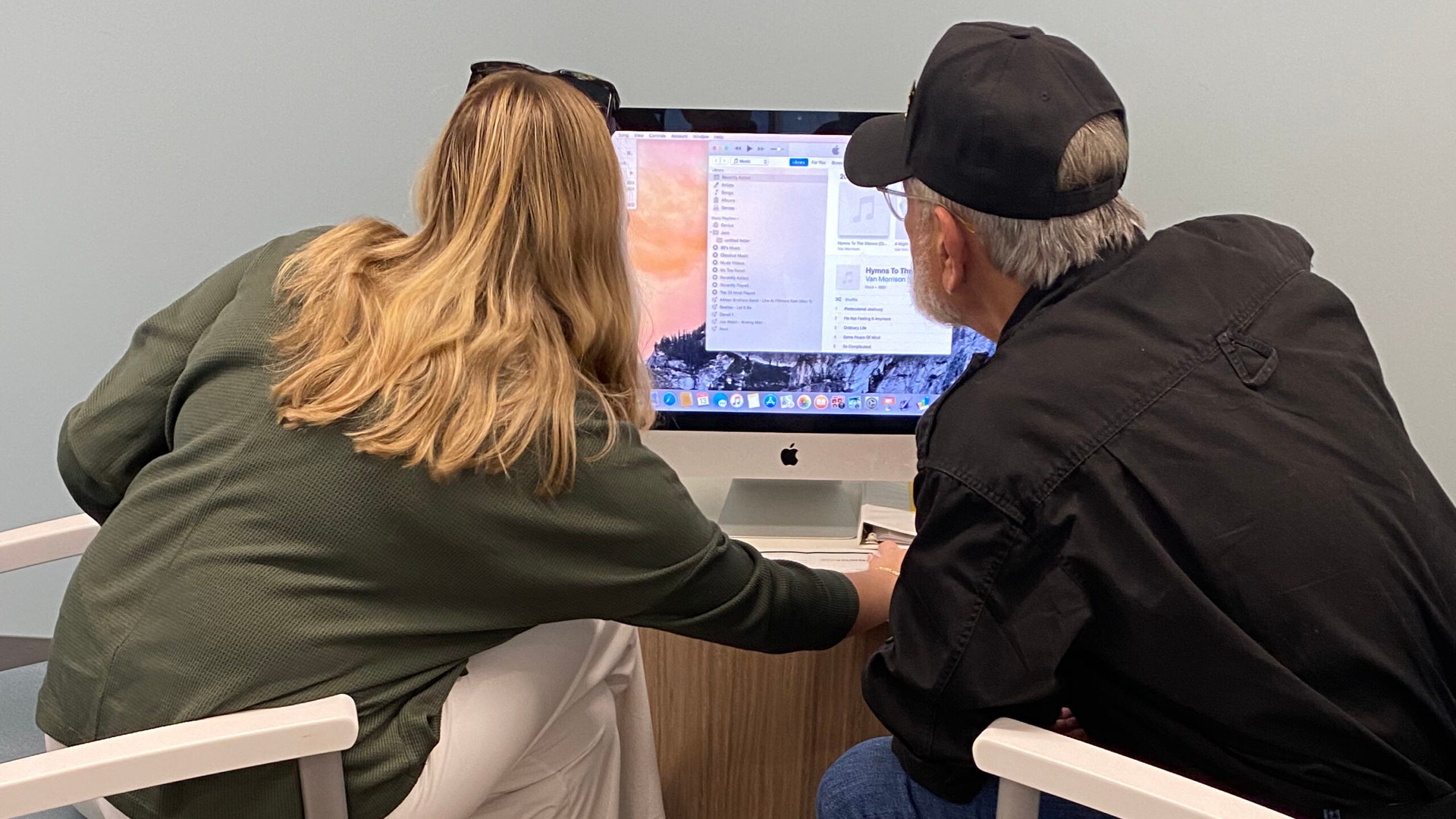 A student sits with a veteran facing a computer screen