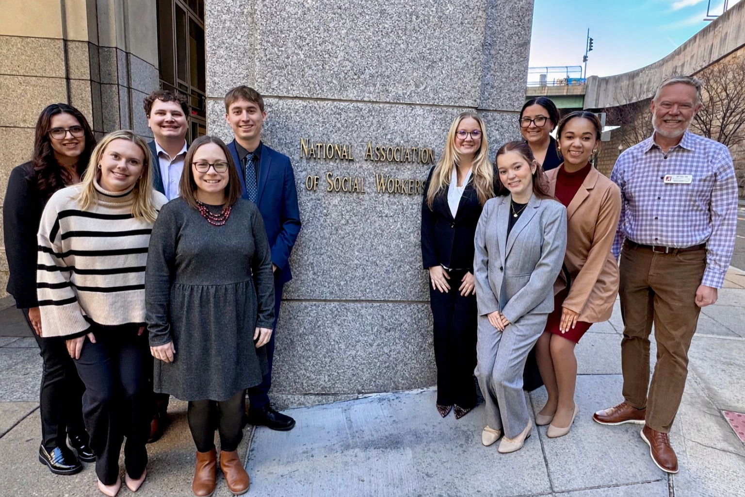 two groups of students stand with their professor outside the National Association of social workers office in Washington, D.C. 
