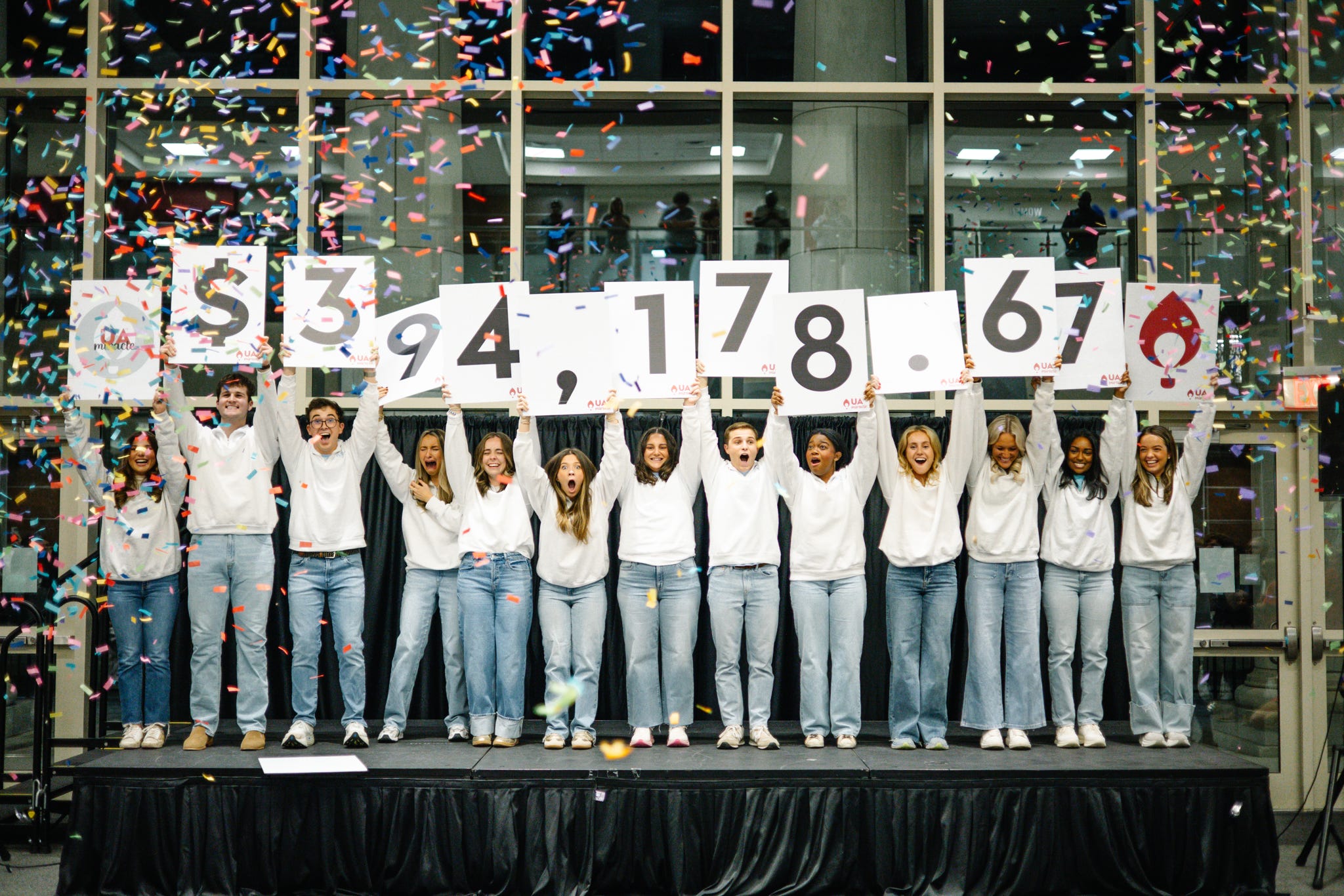 UA Miracle participants holding number cards revealing the total amount raised