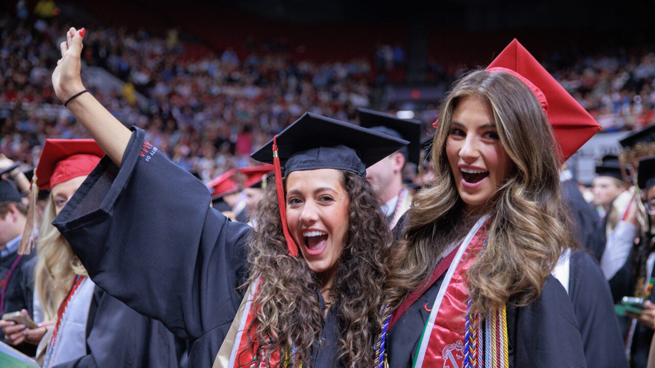 two young ladies cheer during spring commencement