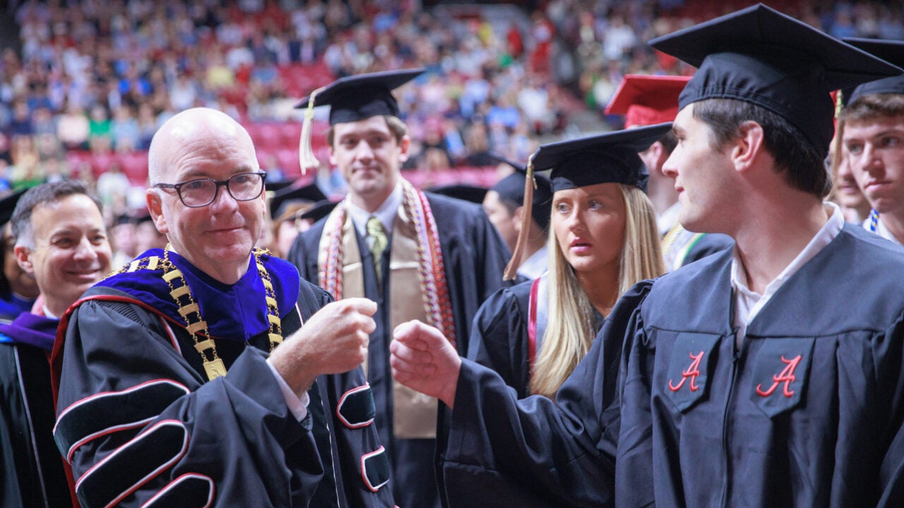 President Mohler gives a fist bmp to a graduate at commencement