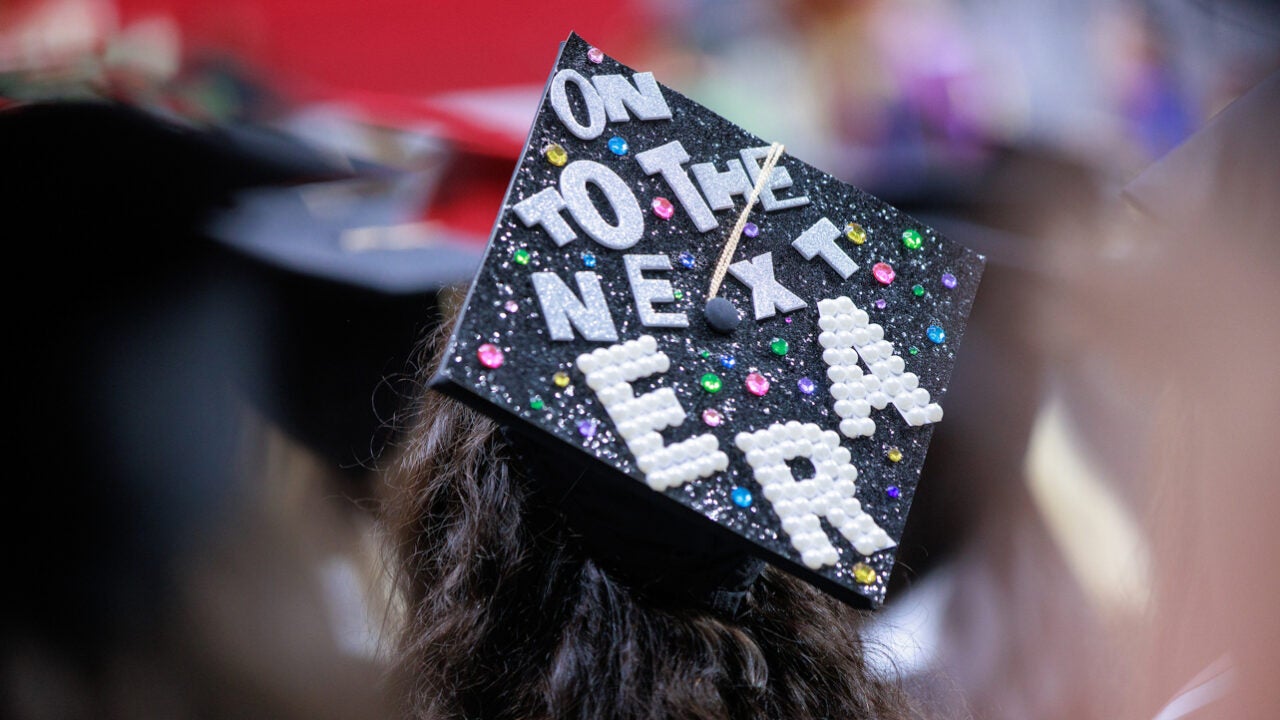 close up on a decorated commencement cap that reads "on to the next era"