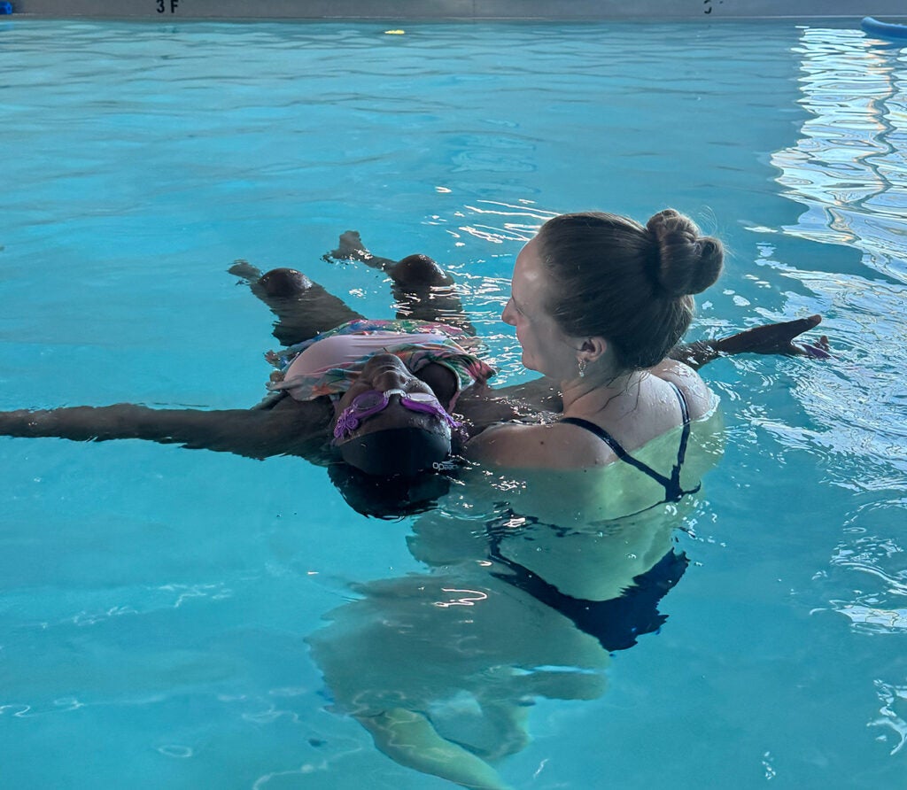 Sydney Blackhurst helps a student float during a swim lesson.