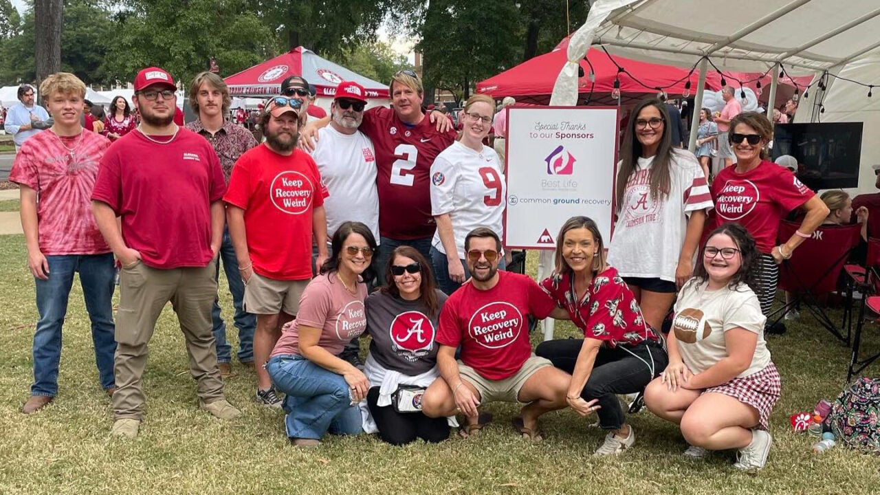 a large group of students wearing crimson and white smile for the camera at a sober tailgate during a UA game day