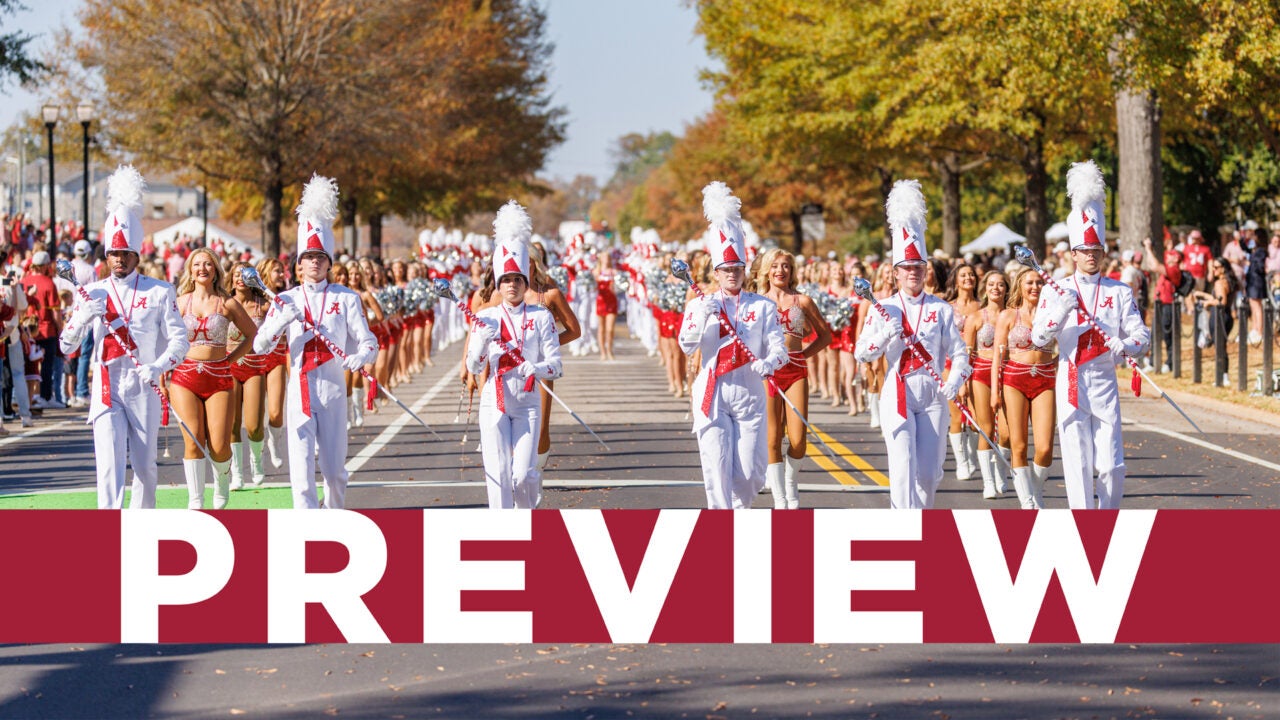 Million Dollar Band drum majors march during the homecoming parade with the Preview banner overlaying